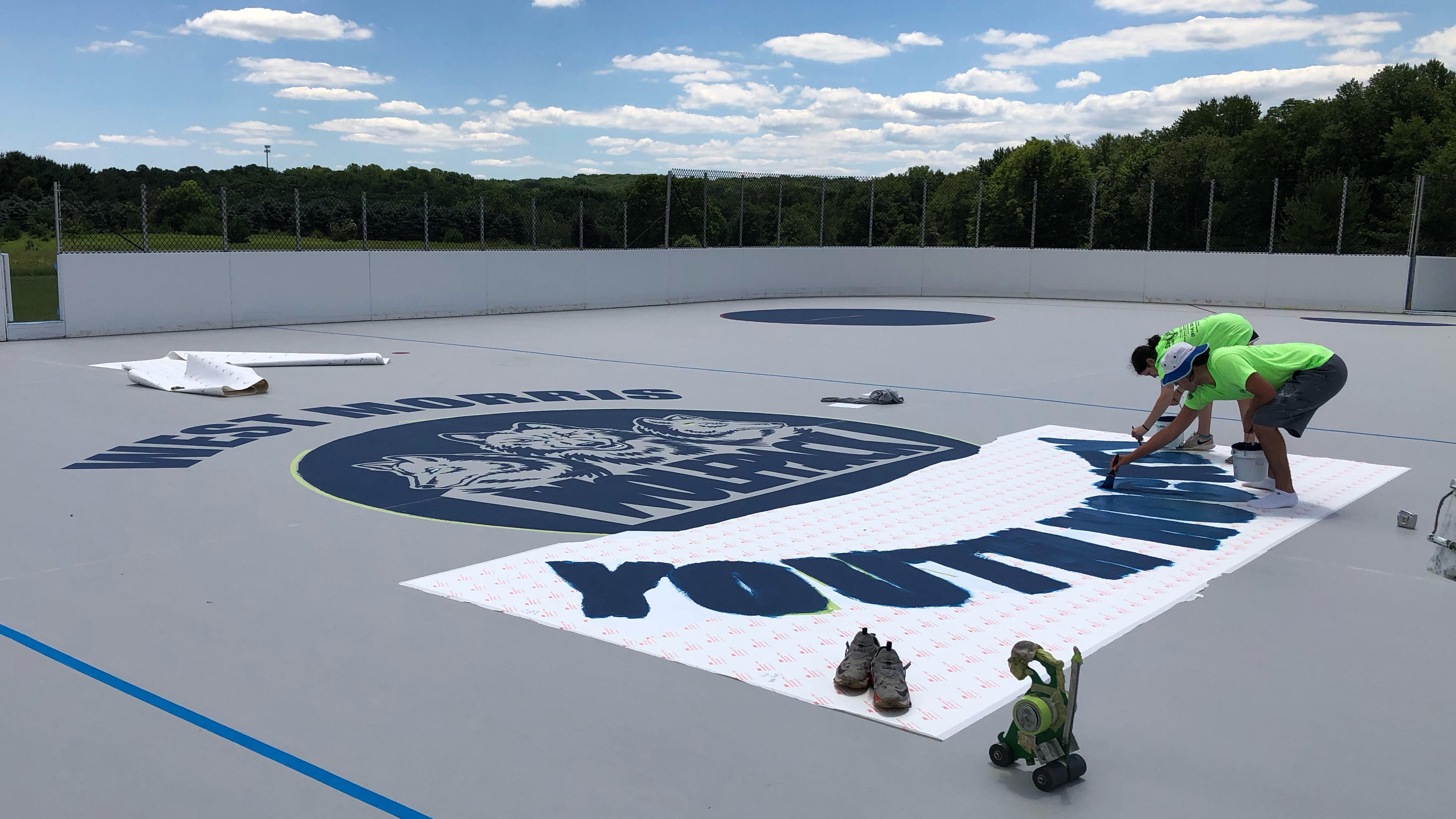 Custom vinyl stencil being installed on a basketball court.