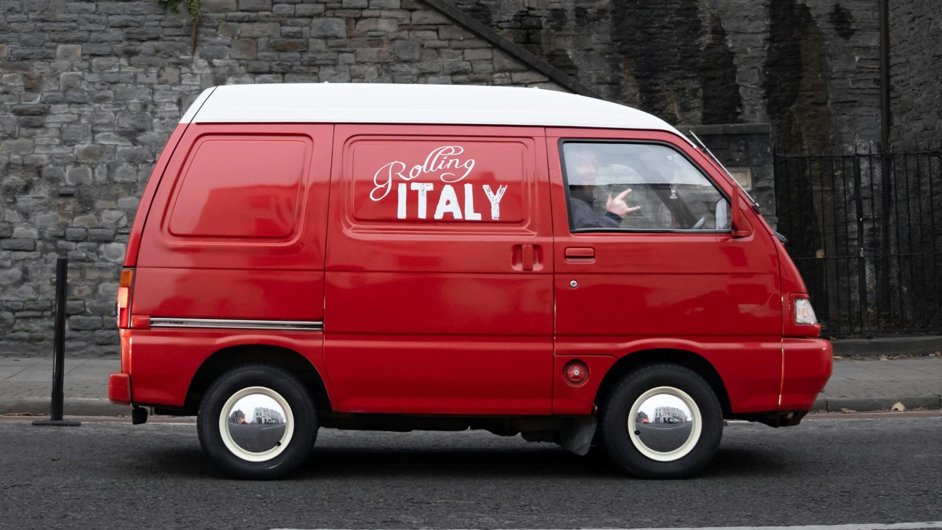 Red mini van displaying a white text custom decal on the side, showcasing custom branding.