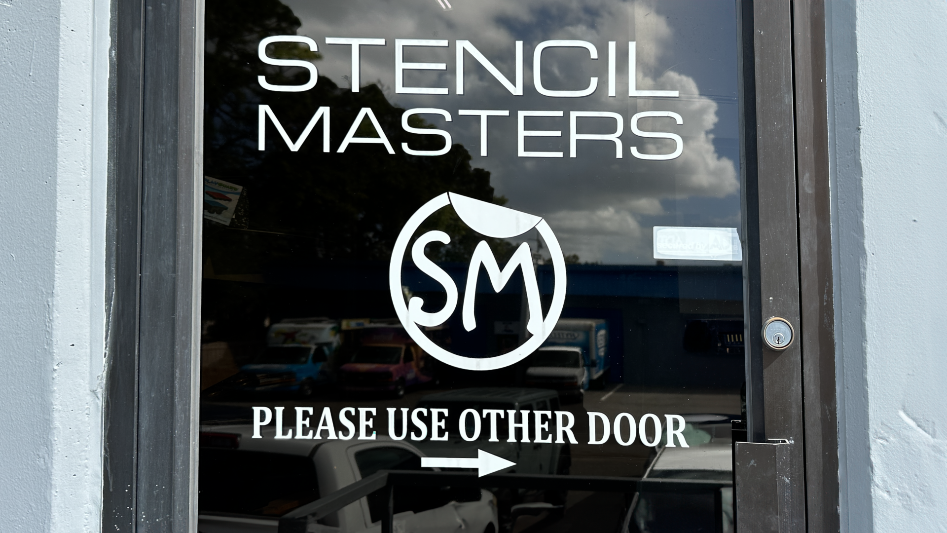 White Stencil Masters custom decal displayed on a door, showing brand visibility and professional finish.